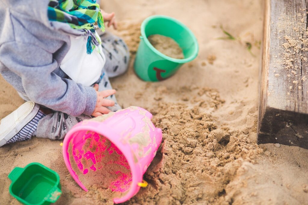 Kind im Sandkasten im Garten